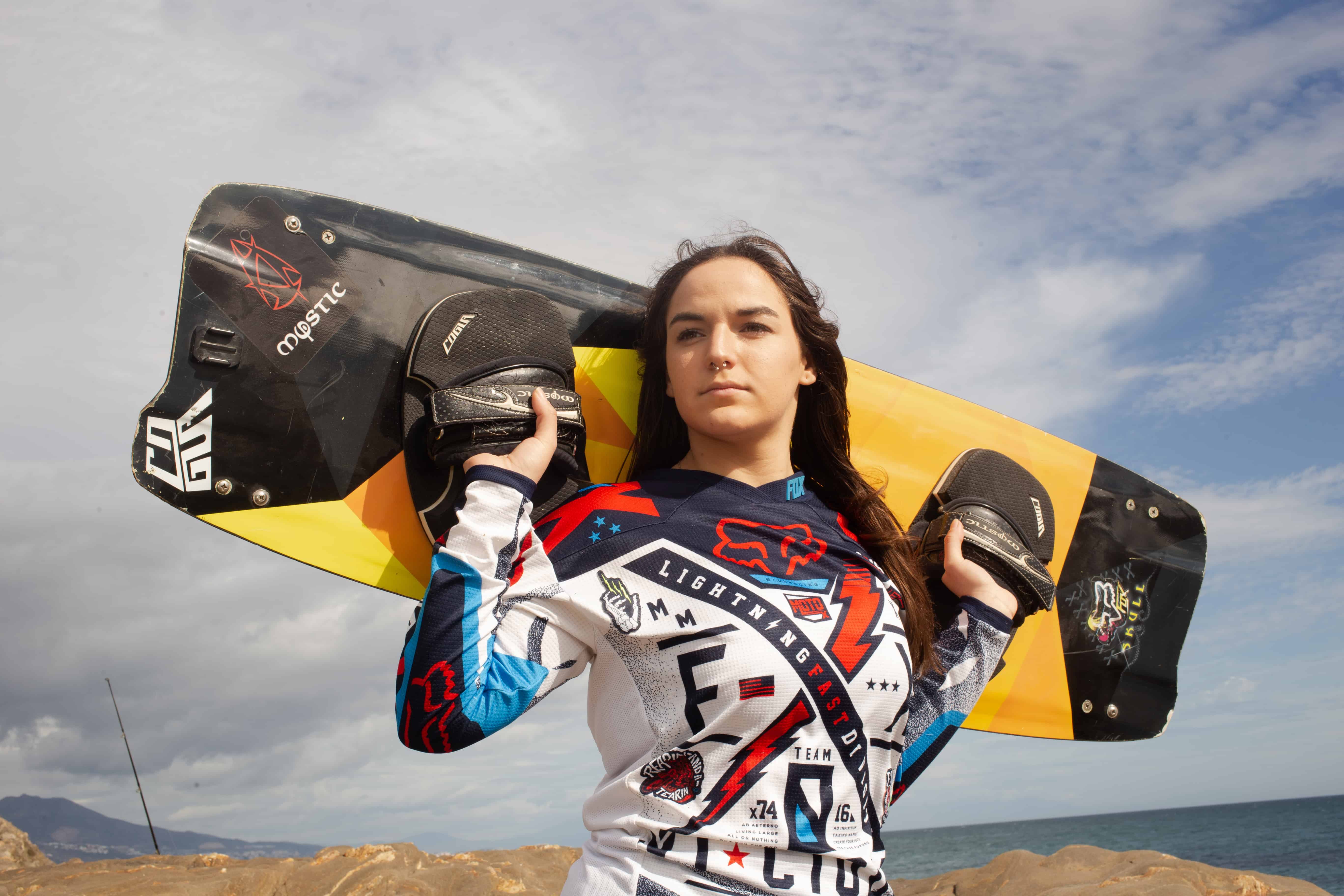 Person holding a surfboard on the beach